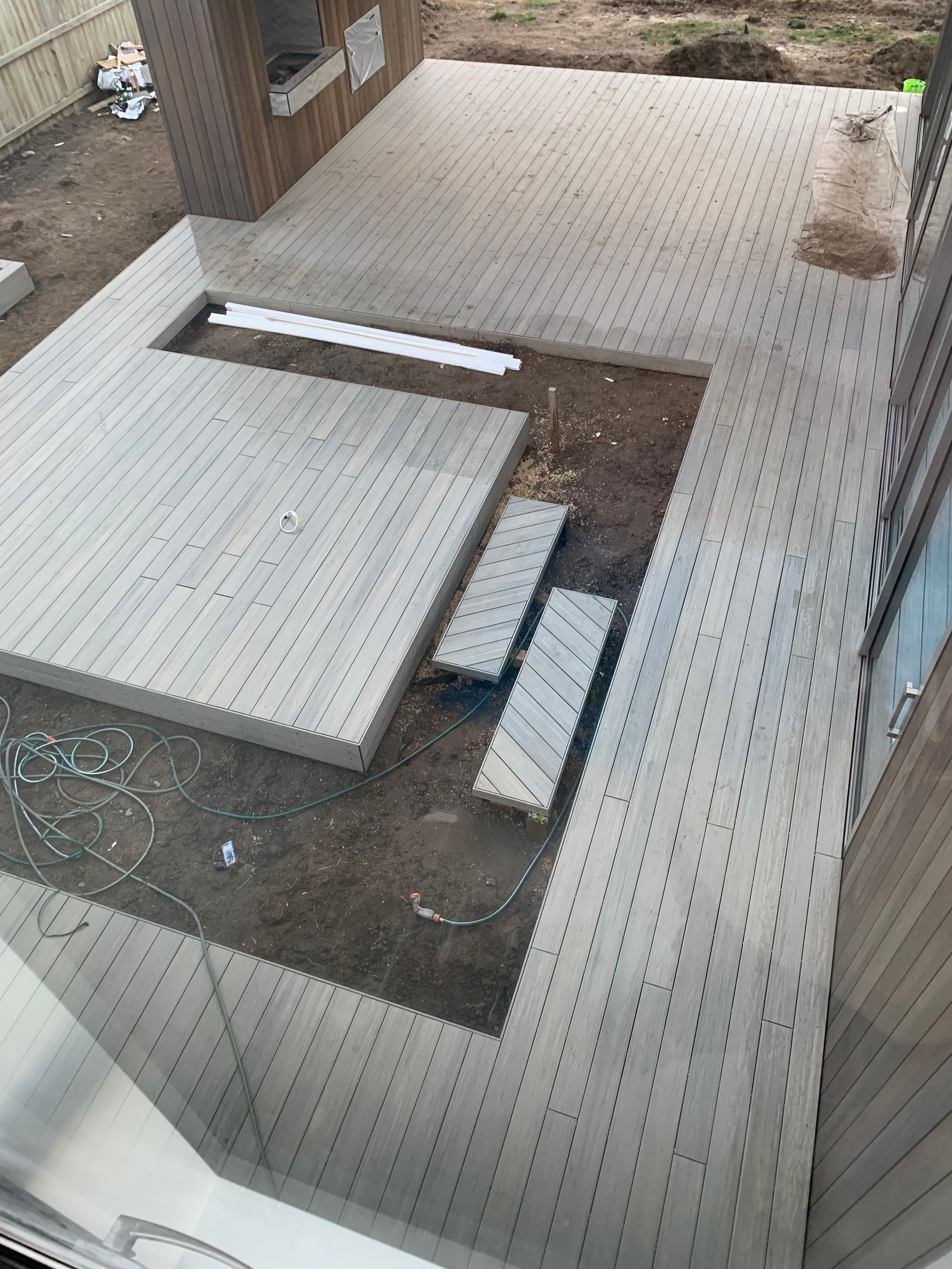 An aerial view of a wooden deck being built in a backyard.