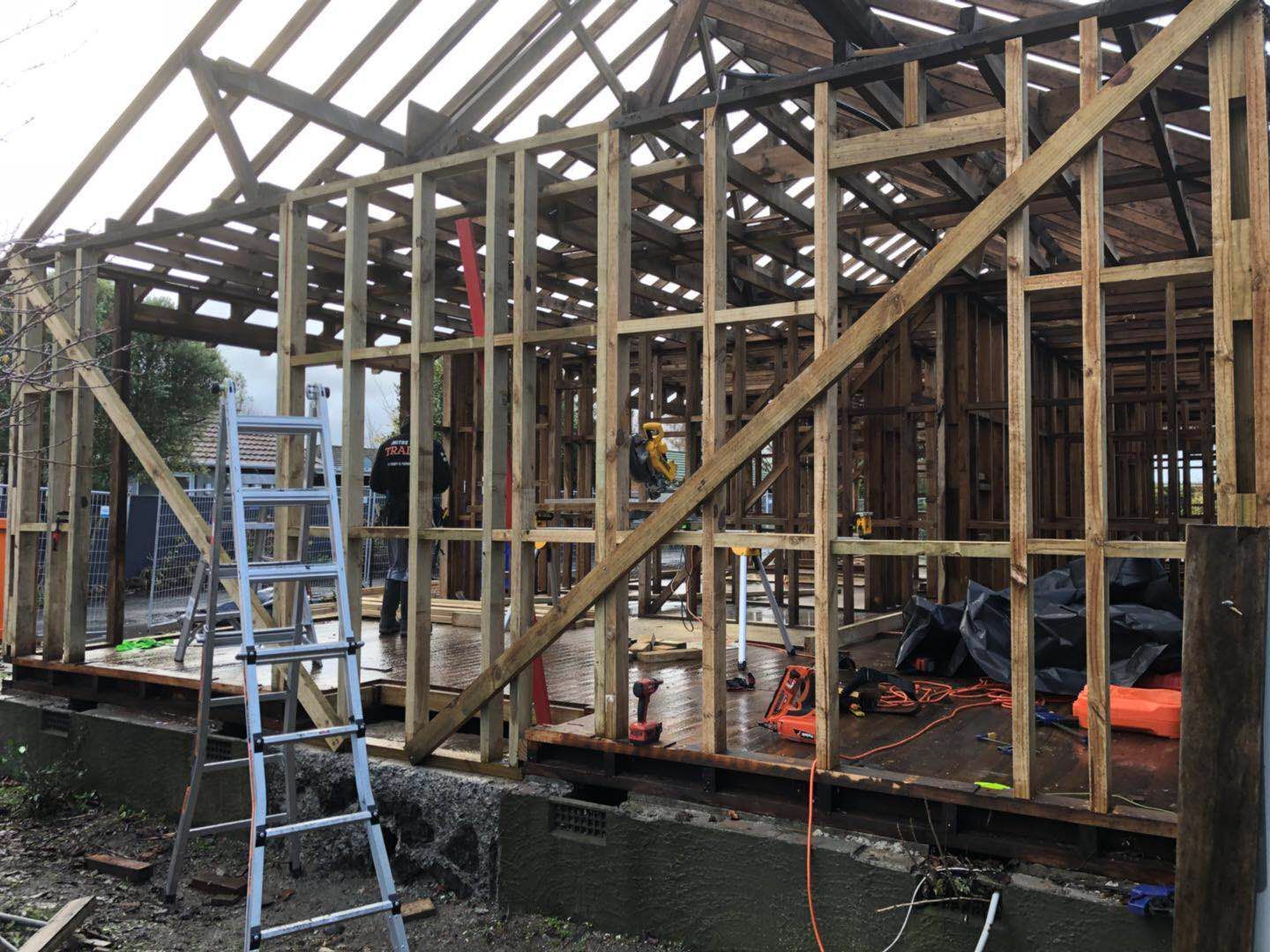 A wooden structure is being built with a ladder in the foreground.