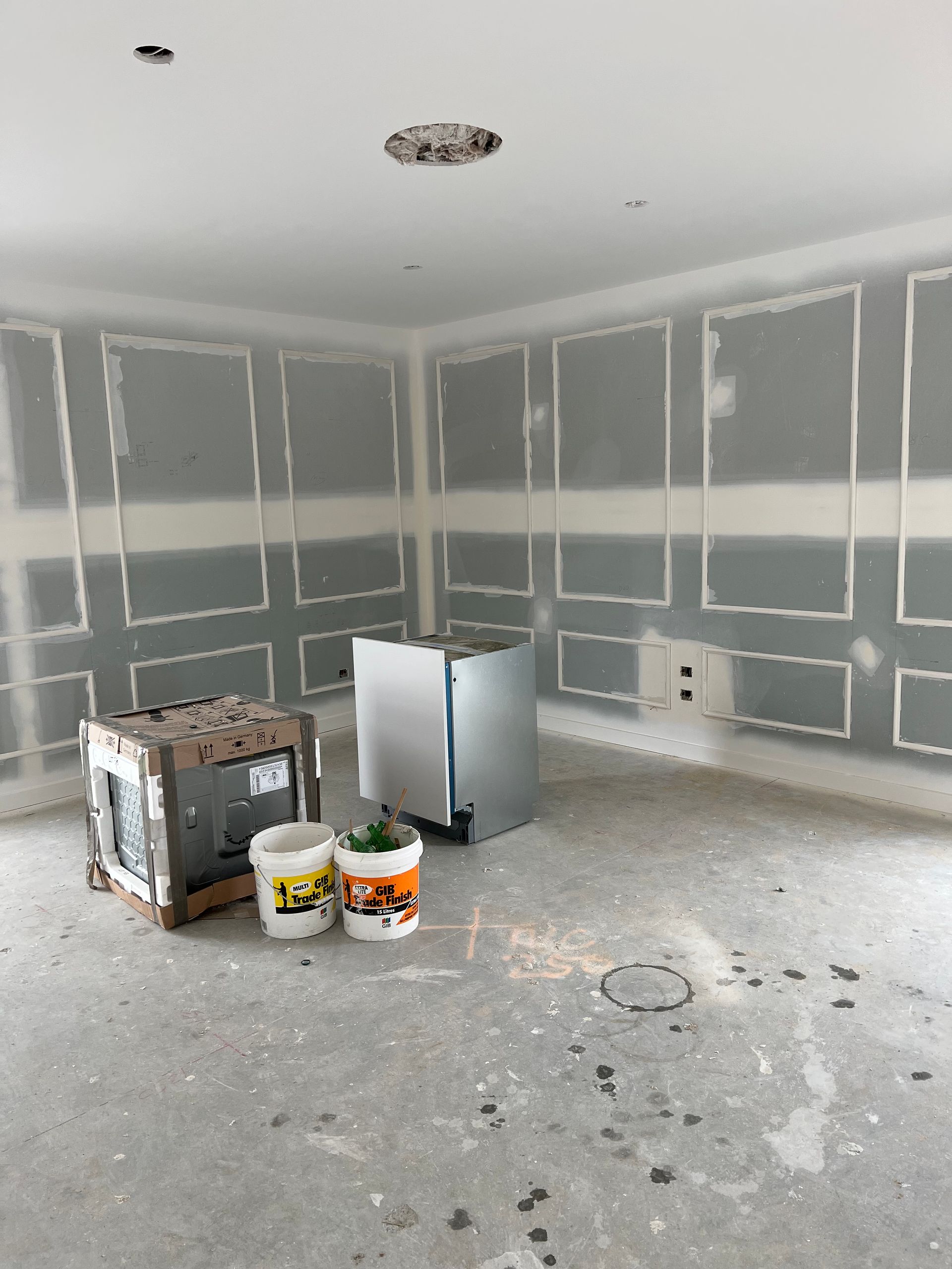 An empty room with buckets of paint on the floor