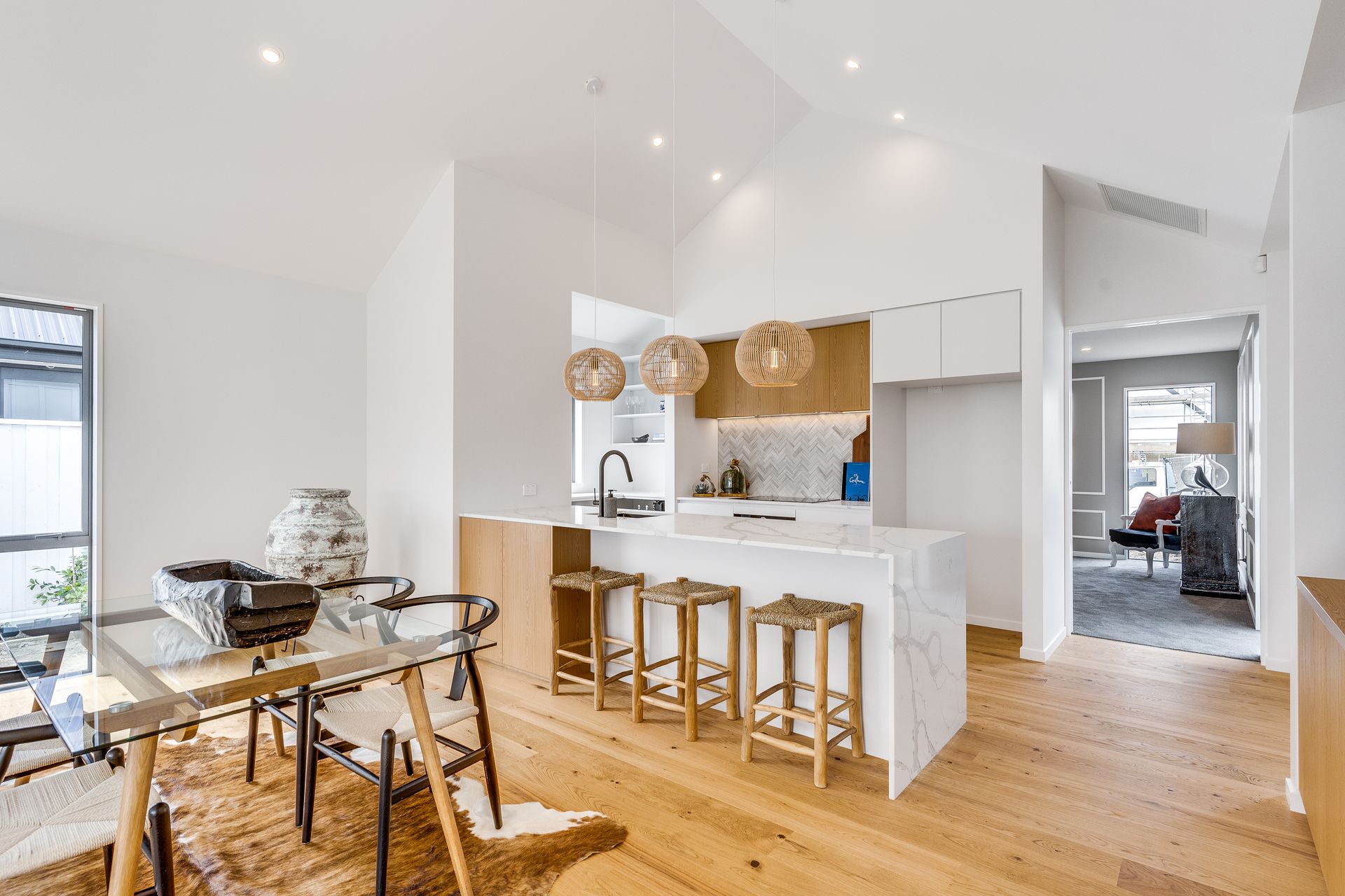A kitchen and dining room in a house with a glass table and chairs.