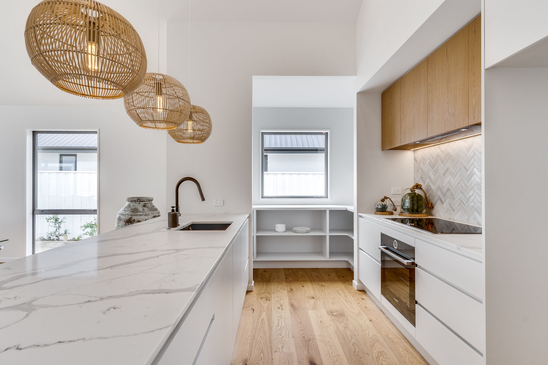 A kitchen with white cabinets and wooden floors and a stove top oven.