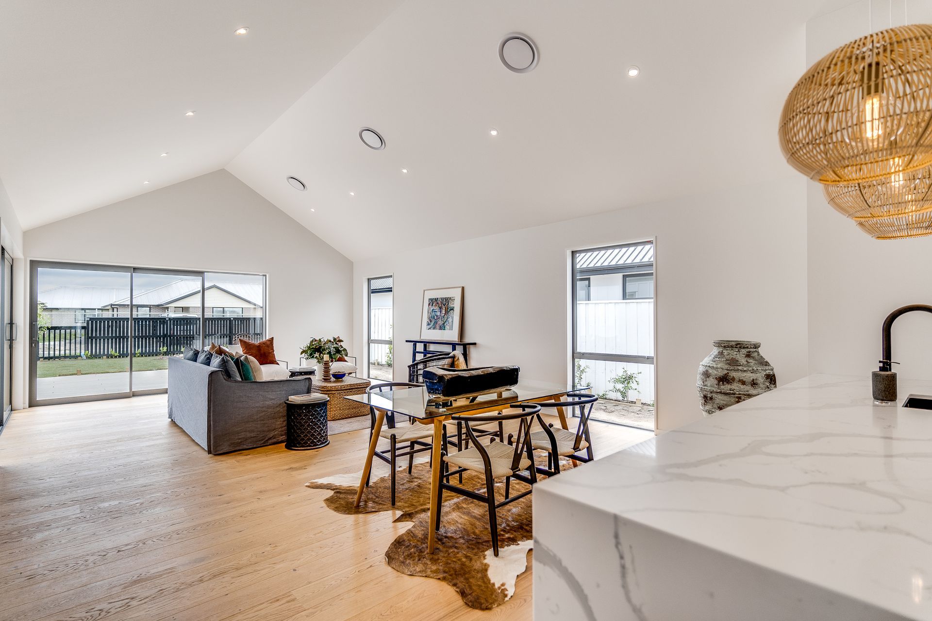 A living room and dining room in a house with a vaulted ceiling.