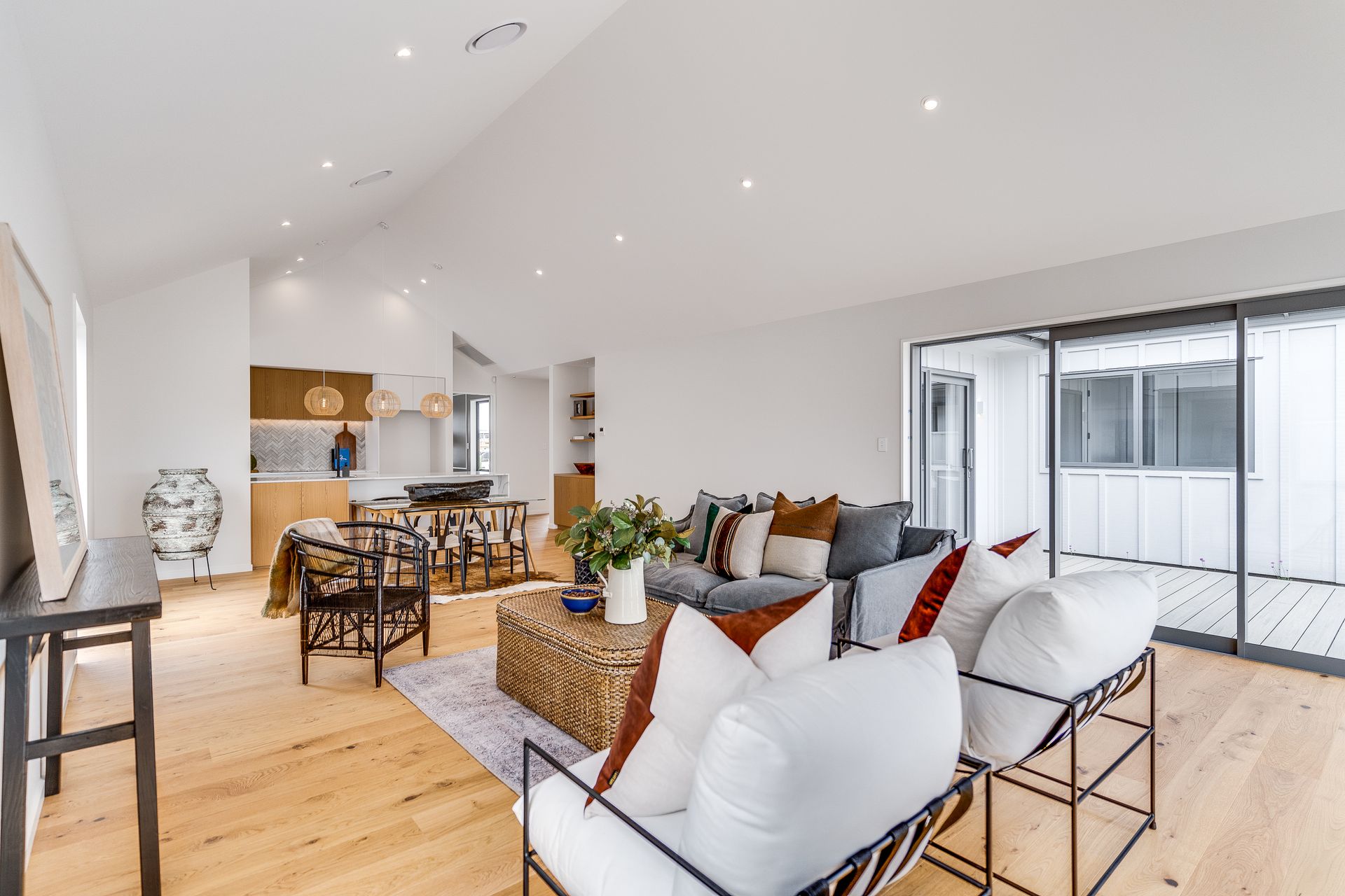 A living room with a couch , chairs , table and sliding glass doors.