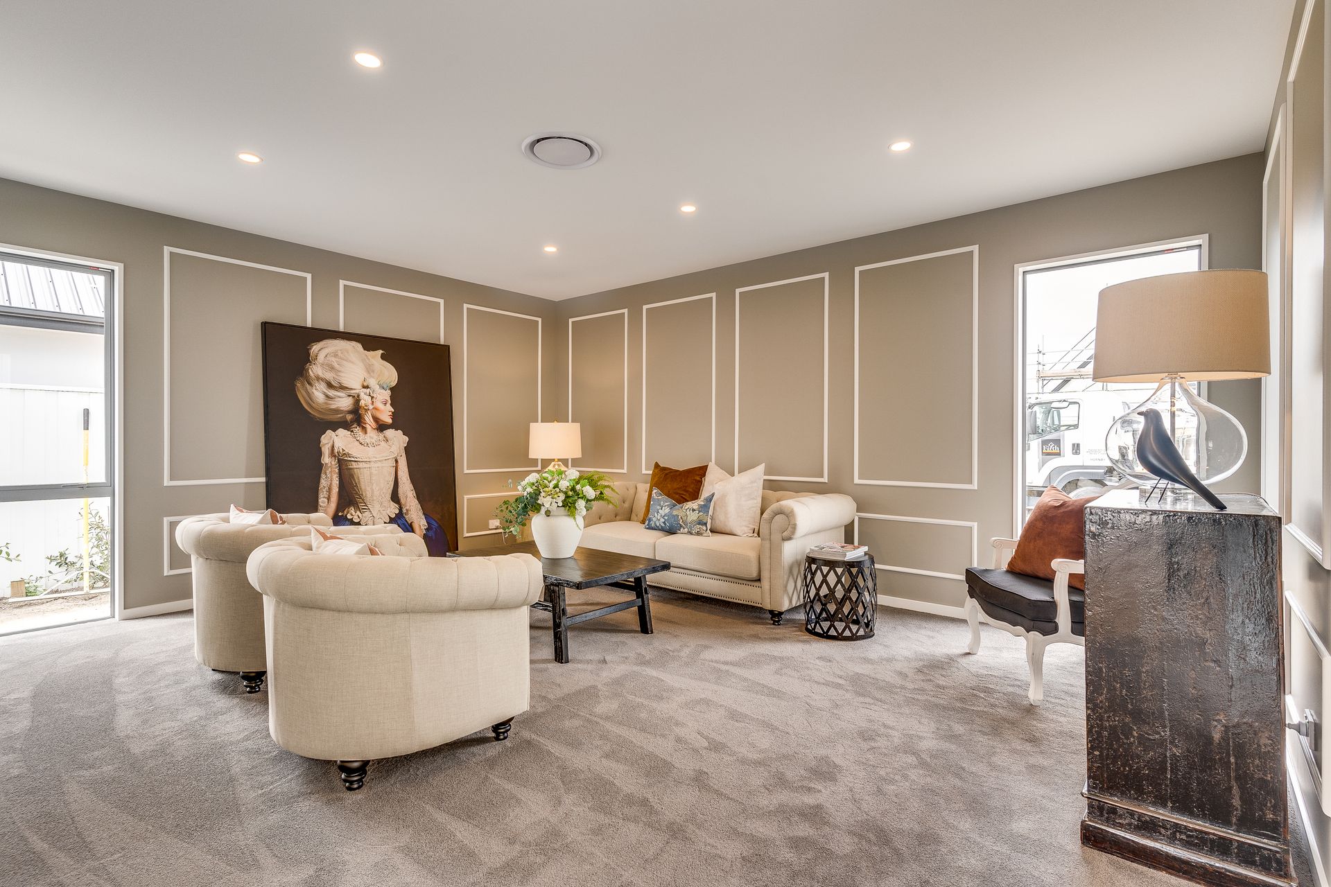 A living room with a couch , chairs , a table and a painting on the wall.
