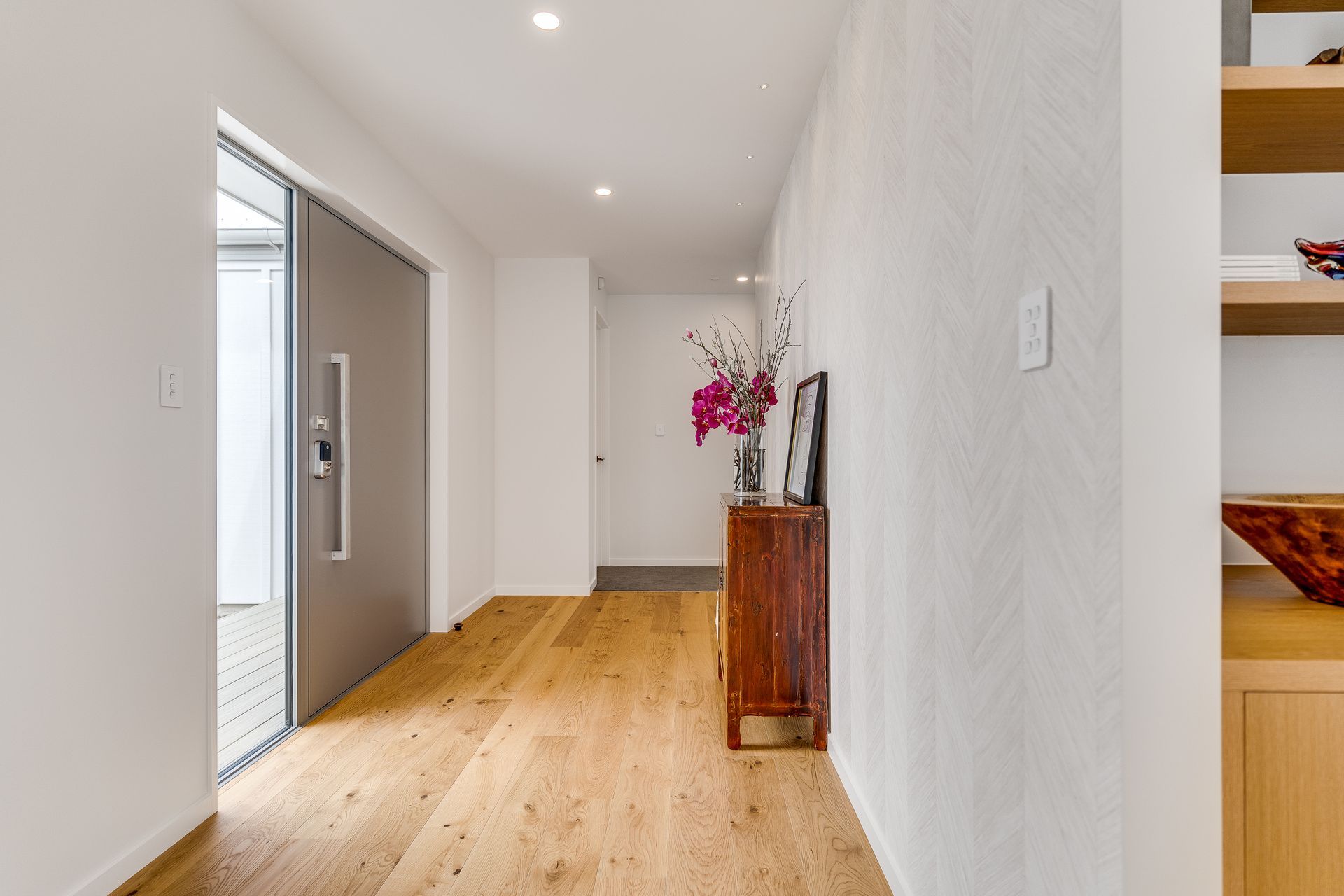 A hallway with hardwood floors and a sliding door in a house.