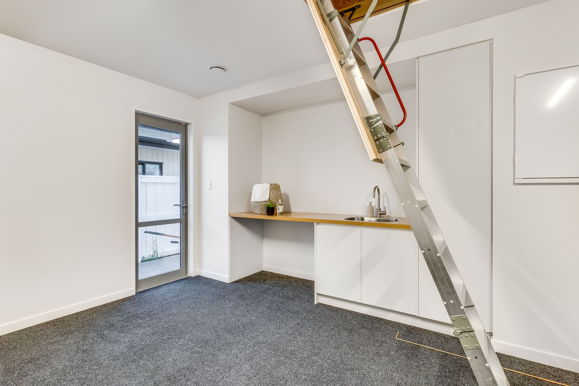 A room with a ladder leading up to the attic.