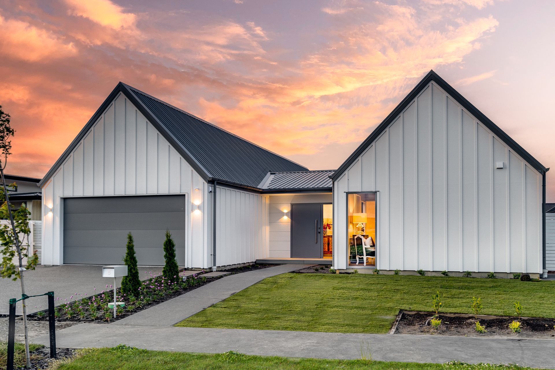 a white house with a black roof and a gray garage door