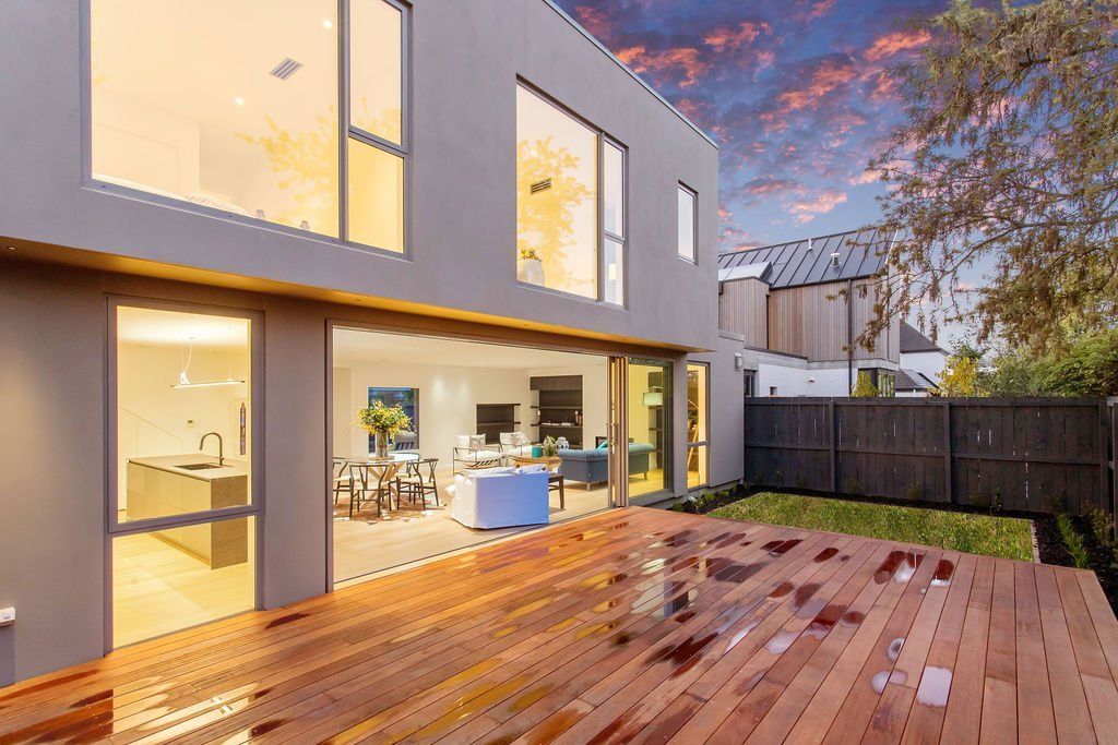 A modern house with a wooden deck in front of it.