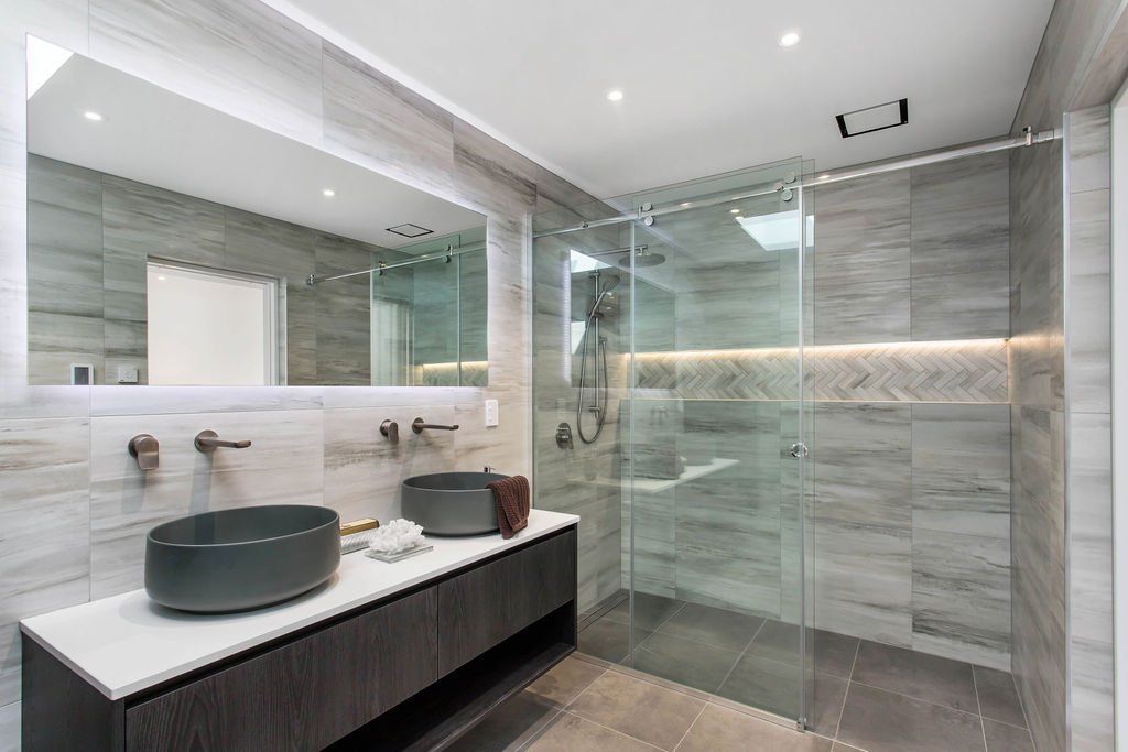 A bathroom with a walk in shower , sink and mirror.