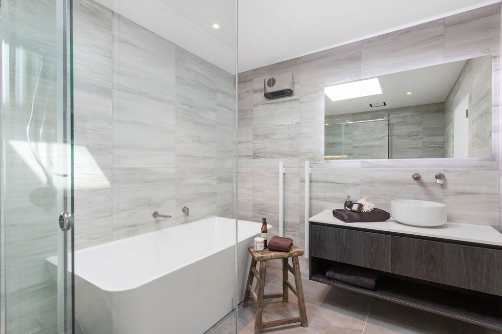 A bathroom with a bathtub , sink , mirror and walk in shower.