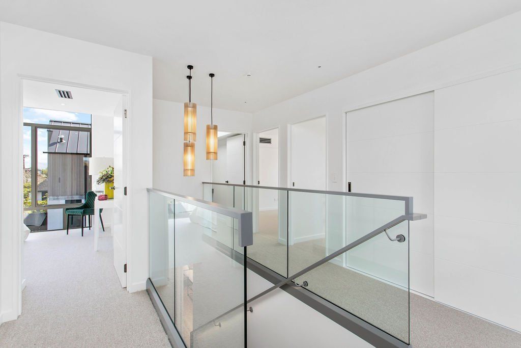 A hallway with a glass railing leading to a living room
