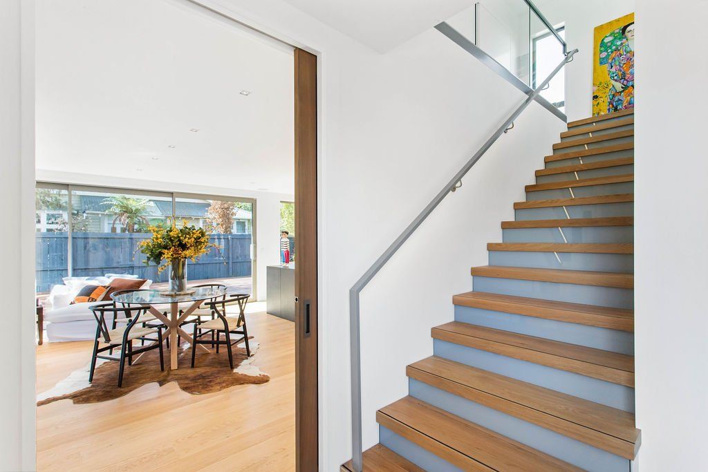 A wooden staircase leading up to a living room with a glass railing.