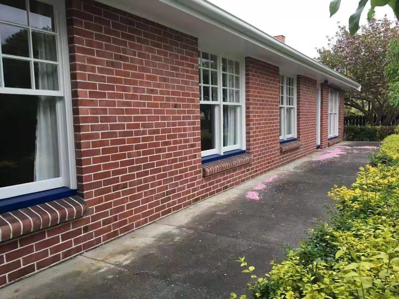 A red brick house with white windows and blue trim