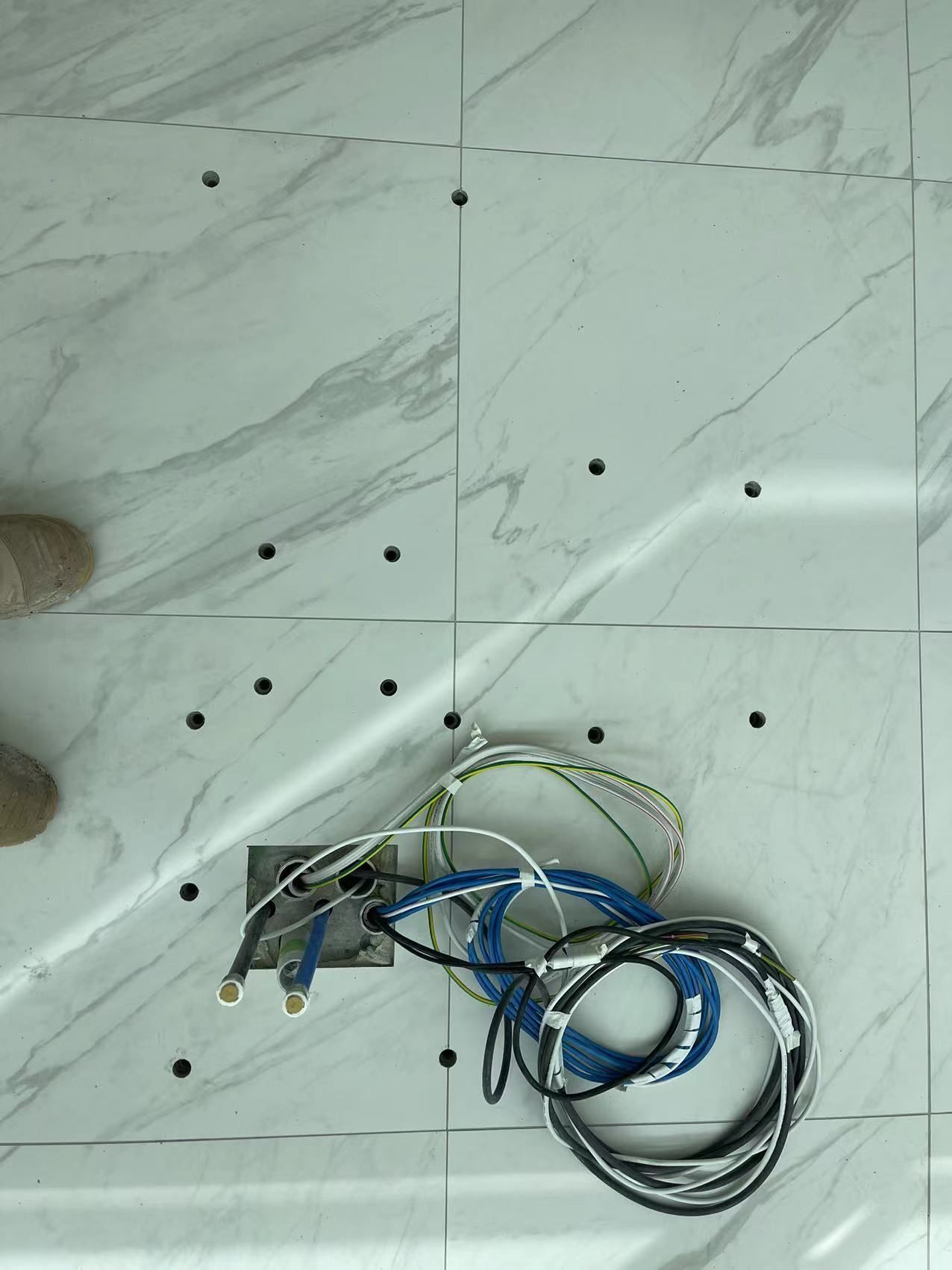 A bunch of wires are laying on a tiled floor