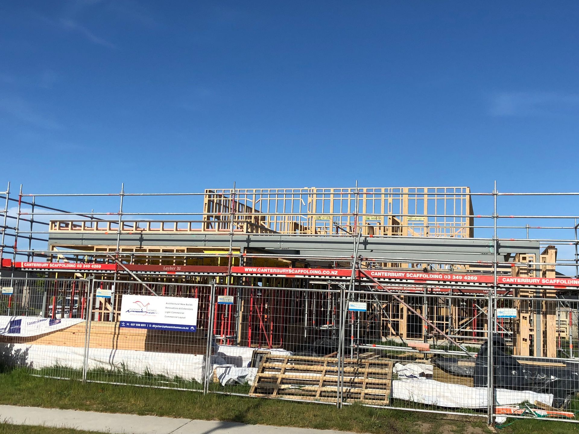 A building under construction with scaffolding and a fence around it.