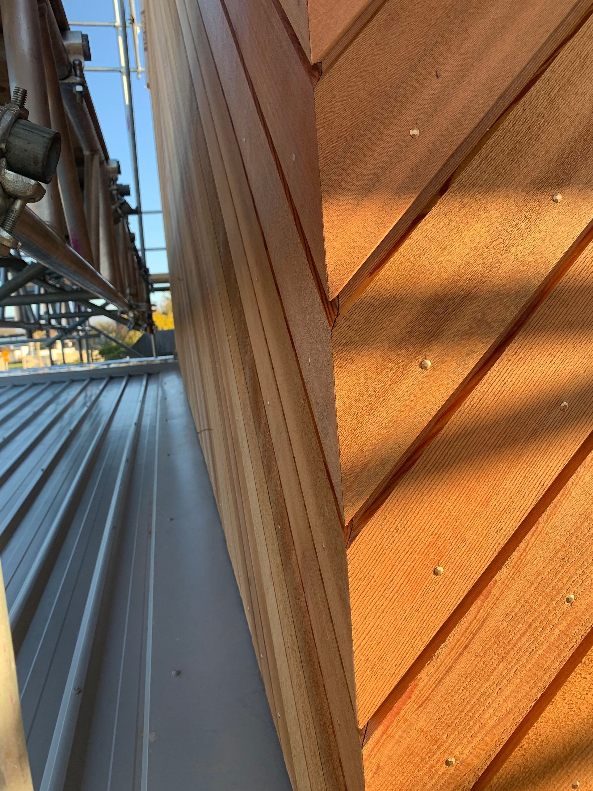 A close up of a wooden wall next to a metal roof.