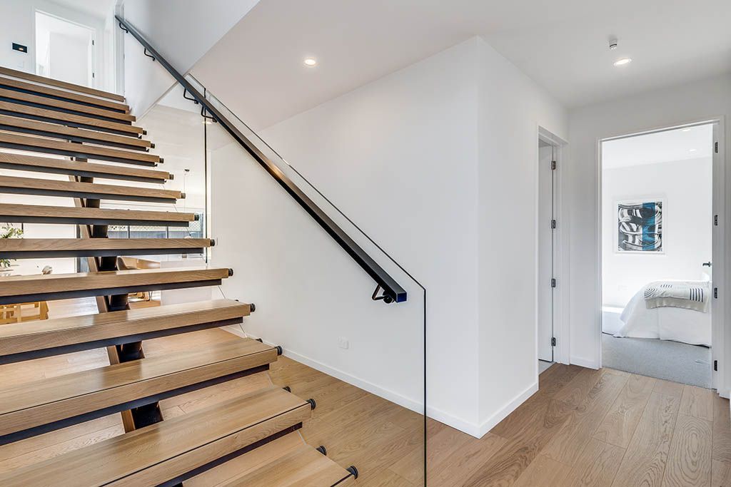 A wooden staircase with a glass railing in a hallway