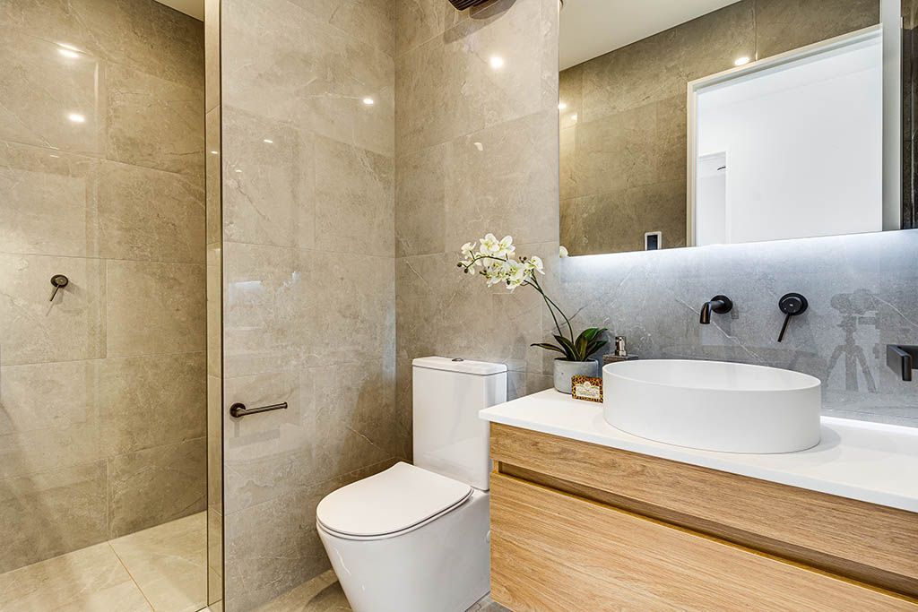 A bathroom with a toilet , sink and walk in shower.