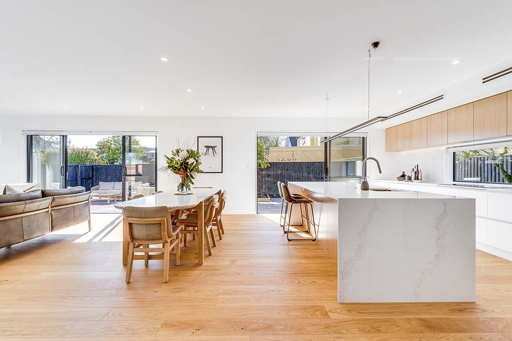 A kitchen and dining room in a house with wooden floors and white cabinets.