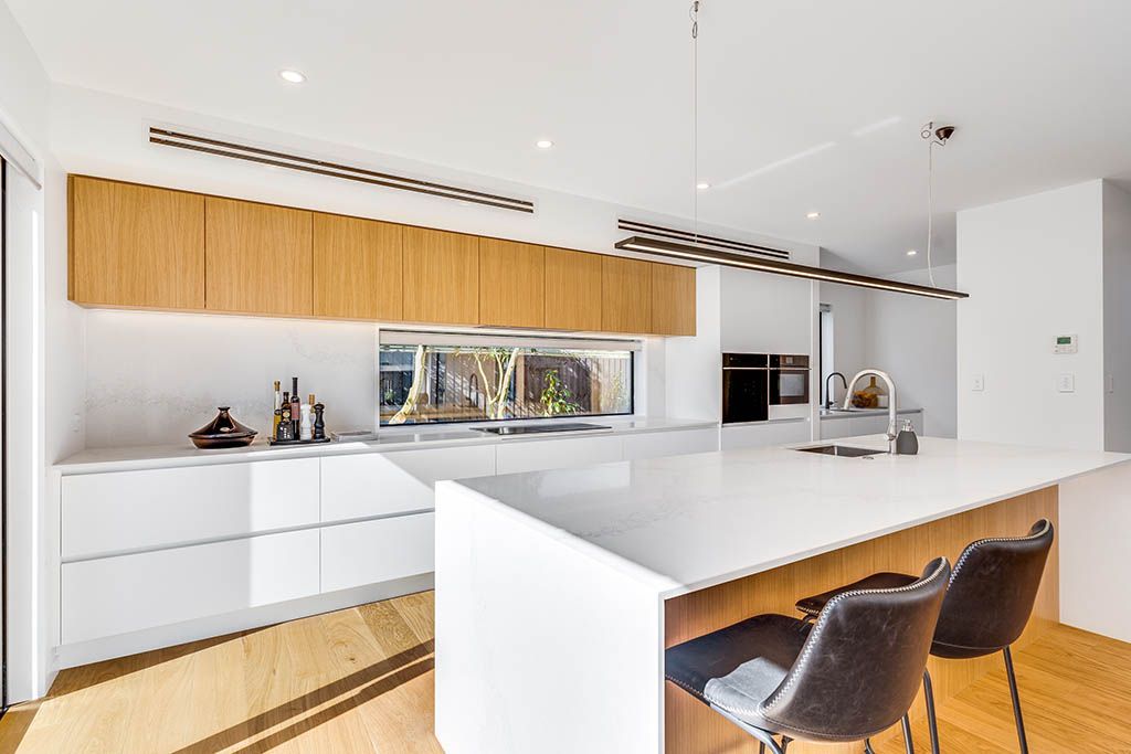 A kitchen with white cabinets and wooden cabinets and a large island.