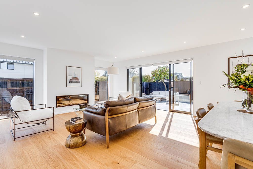 A living room with a couch , table , chairs and sliding glass doors.