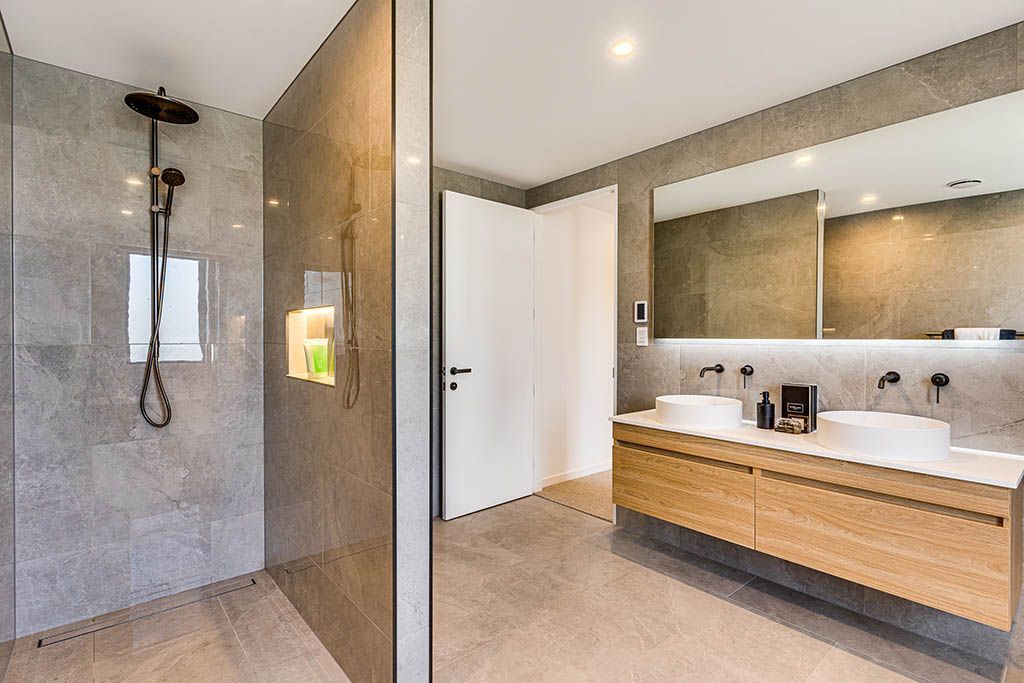 A bathroom with a walk in shower and two sinks.