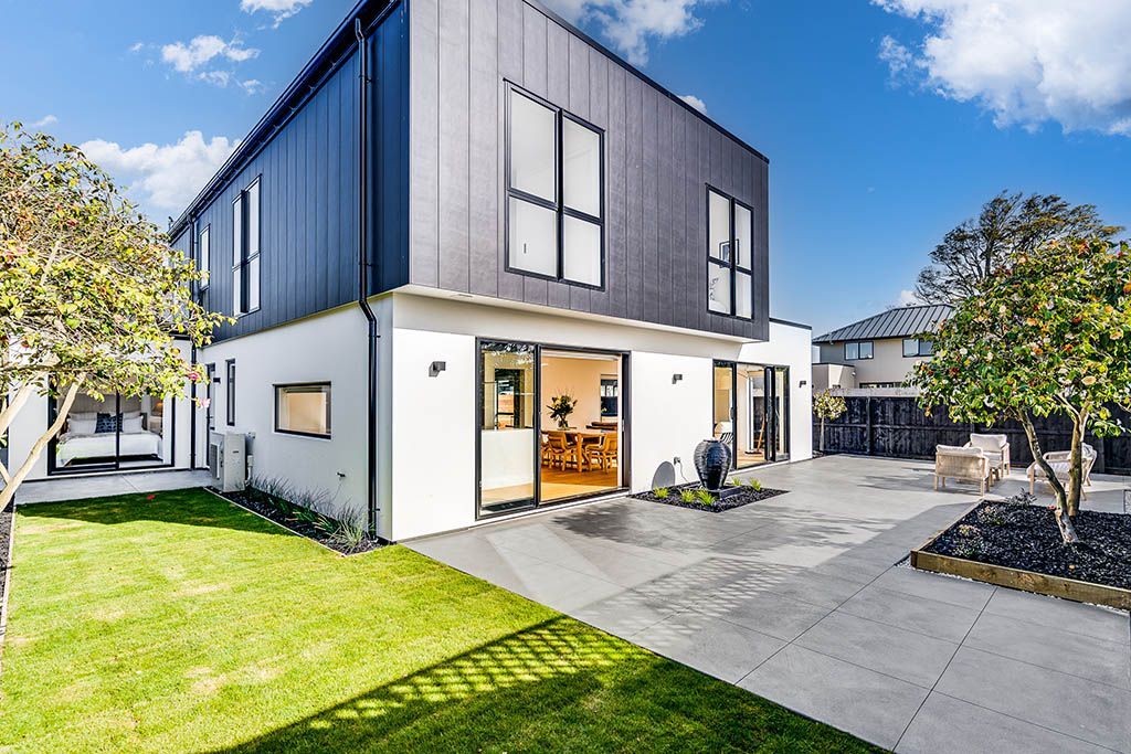 A large white house with a black roof is sitting on top of a lush green lawn.