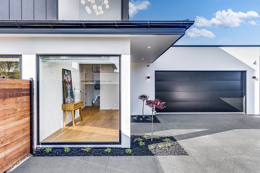 A white house with a black garage door and a large window