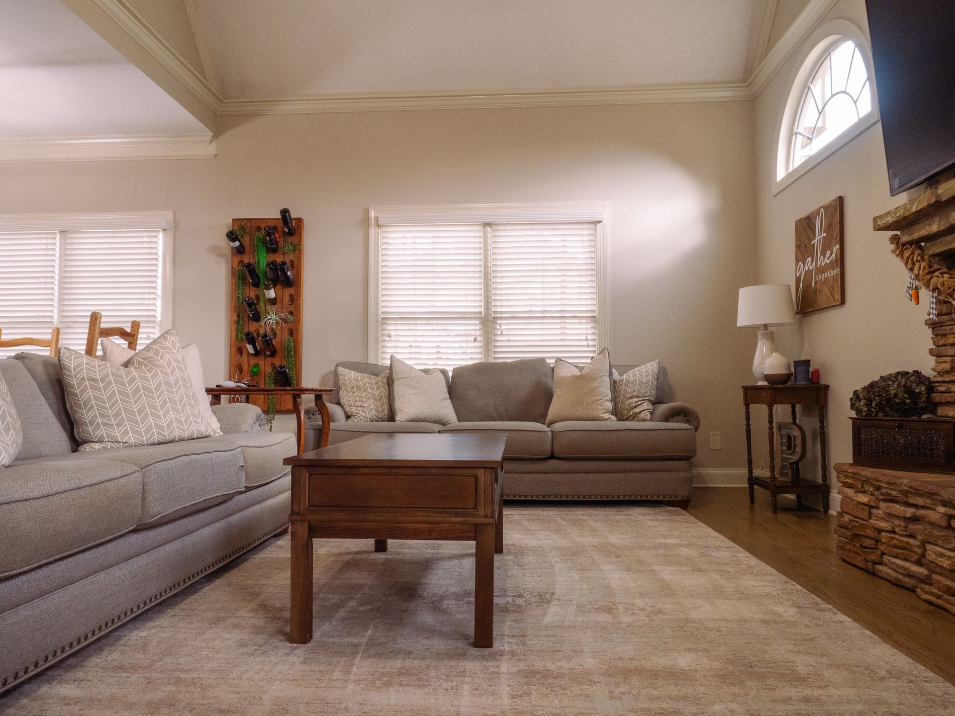 Living room with fresh vacuumed carpet wood table and fluffed throw pillow with stone fireplace
