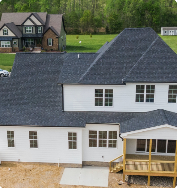 An aerial view of a white house with a black roof
