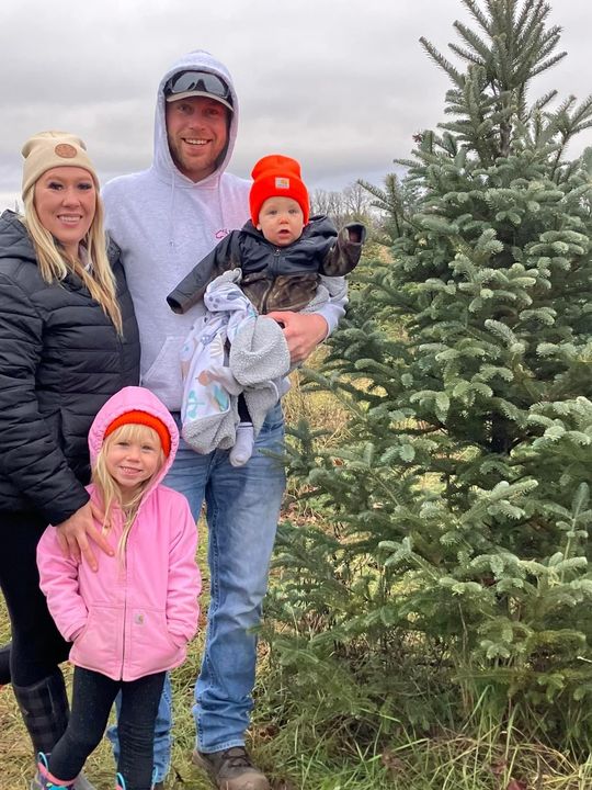 A family is posing for a picture in front of a christmas tree.