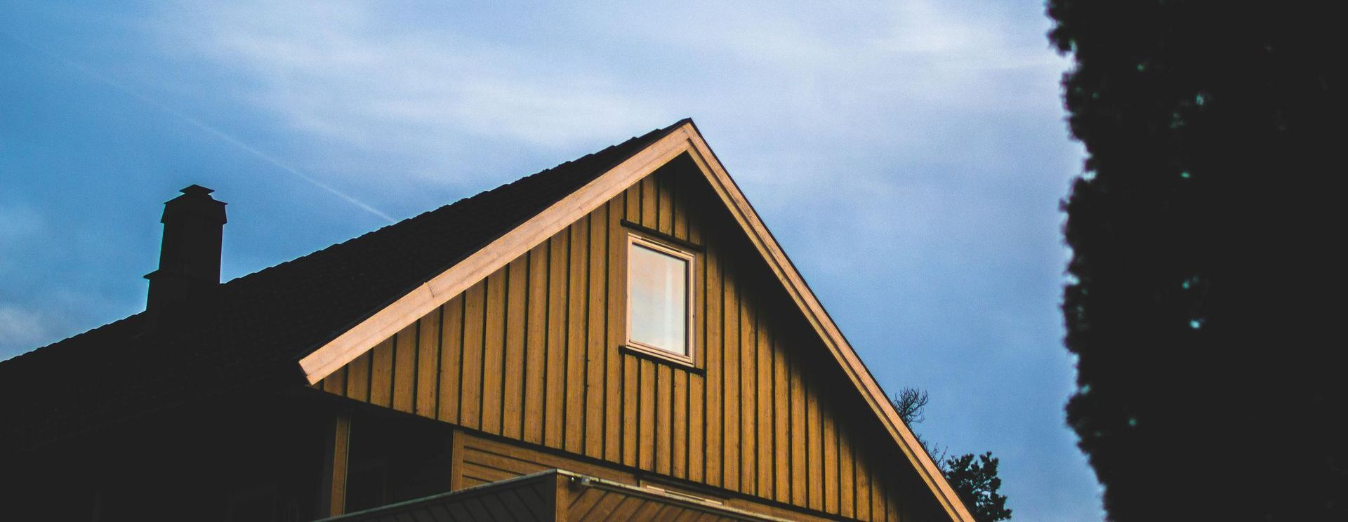 A wooden house with a window on the roof and a chimney.