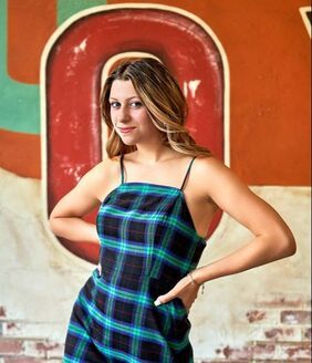 Photos of senior portrait session. Young woman with brown hair wearing a plaid dress.