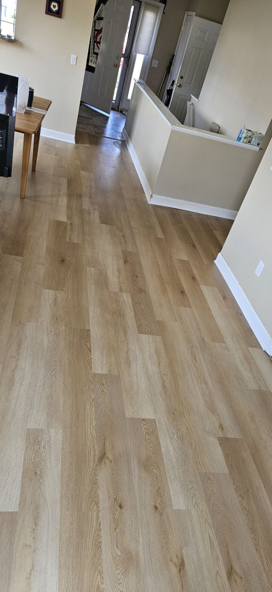 A room with light wood-look laminate flooring. A short wall and door are visible.