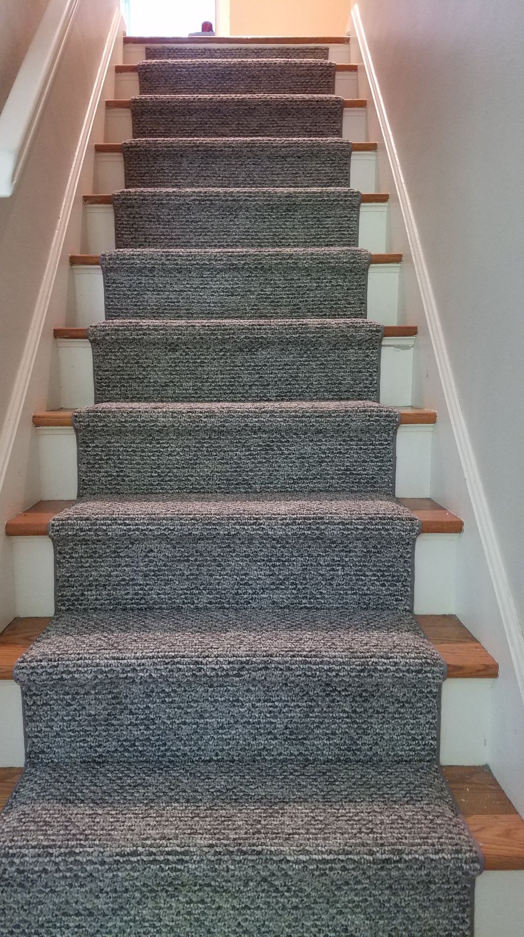 Staircase with gray and white patterned carpet runner on wooden steps.