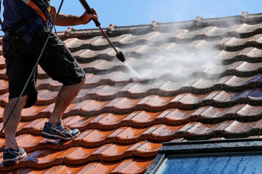 A Man is Cleaning a Roof With a High Pressure Washer — Roofpoint In Kawungan, QLD