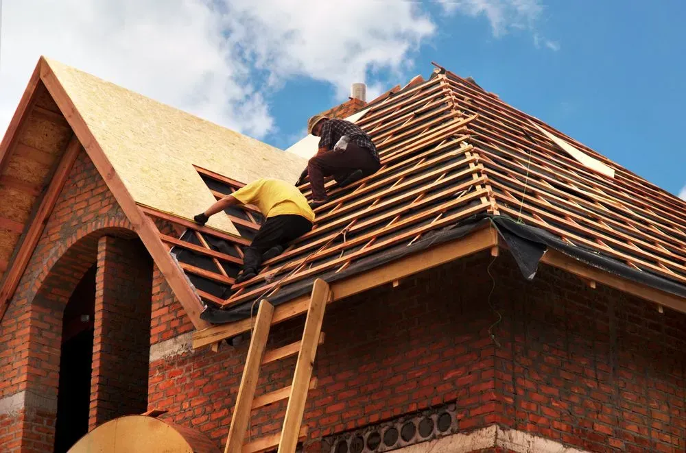 Two Men Are Working on the Roof of a Brick House — Roofpoint In Kawungan, QLD