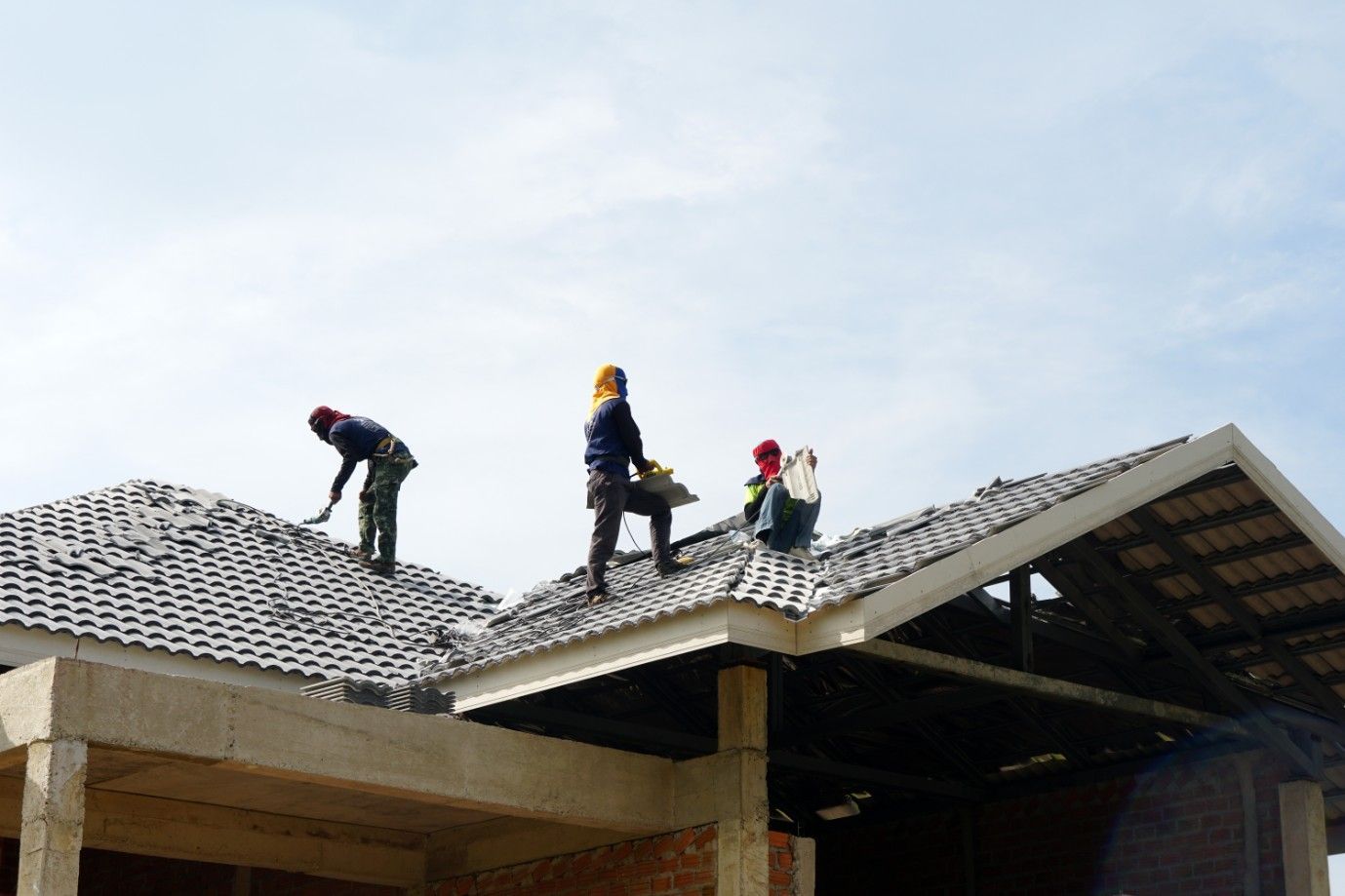 A Group of Construction Workers Are Working on the Roof of a House — Roofpoint In Kawungan, QLD