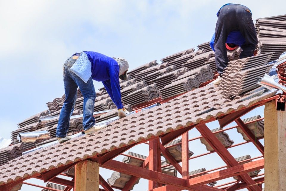 Two Men Are Working on the Roof of a Building — Roofpoint In Maryborough, QLD