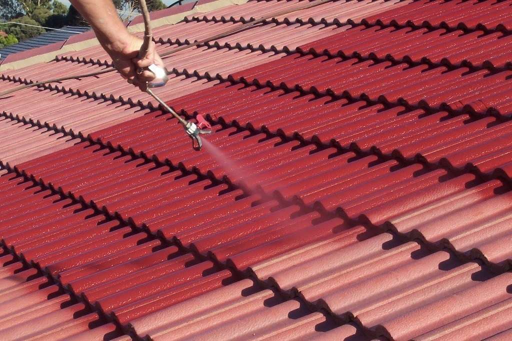 A Person is Spraying Paint on a Red Roof — Roofpoint In Maryborough, QLD