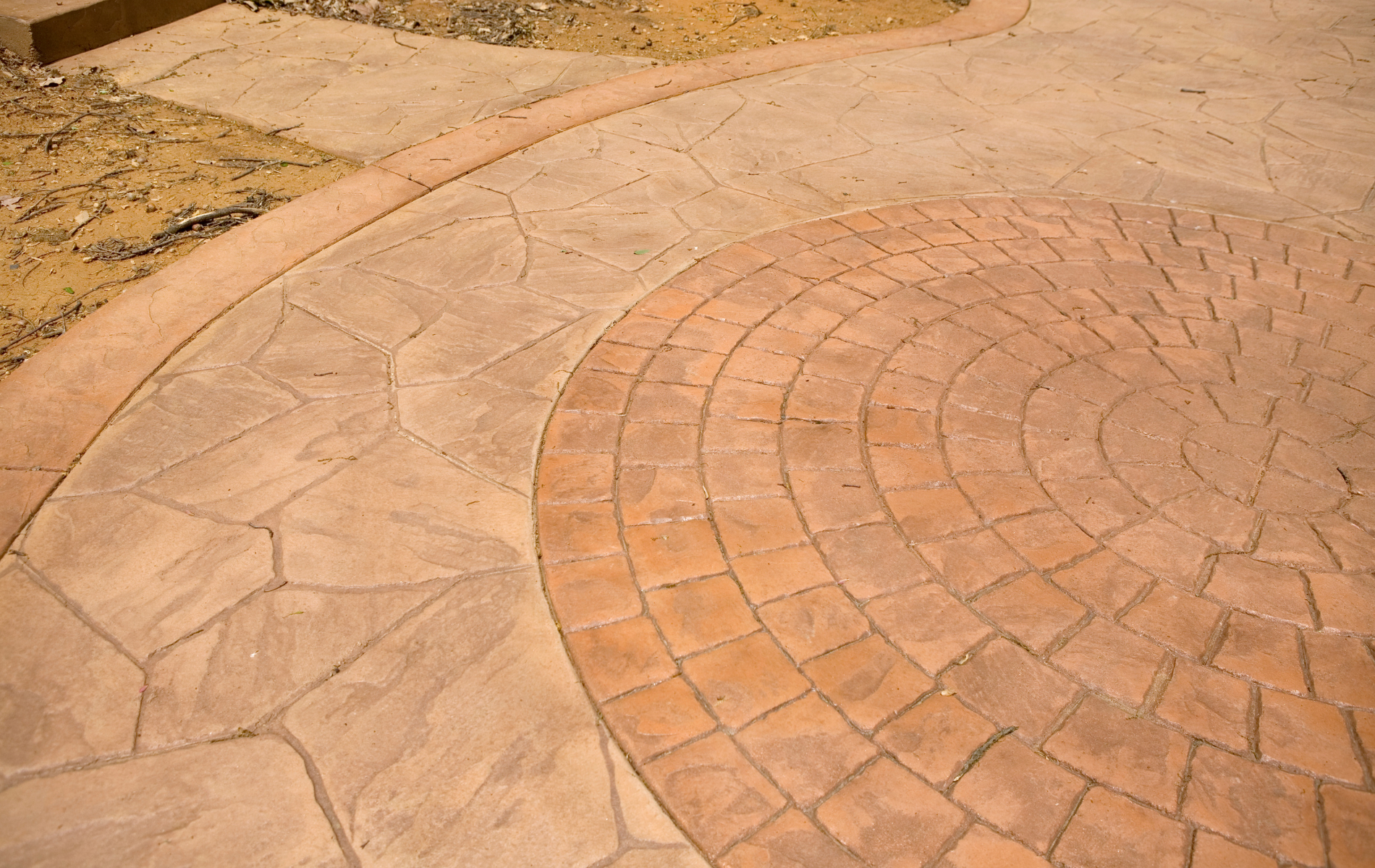 Stamped concrete patio with circular brick pattern and flagstone border.