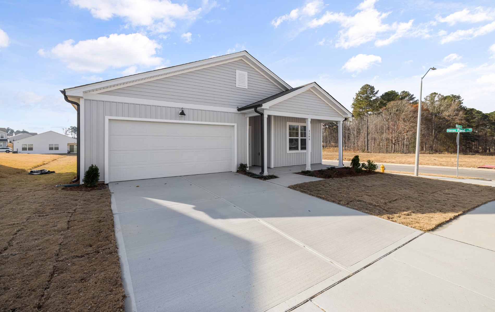 Gray house with a two-car garage, concrete driveway, and small front porch on a corner lot.