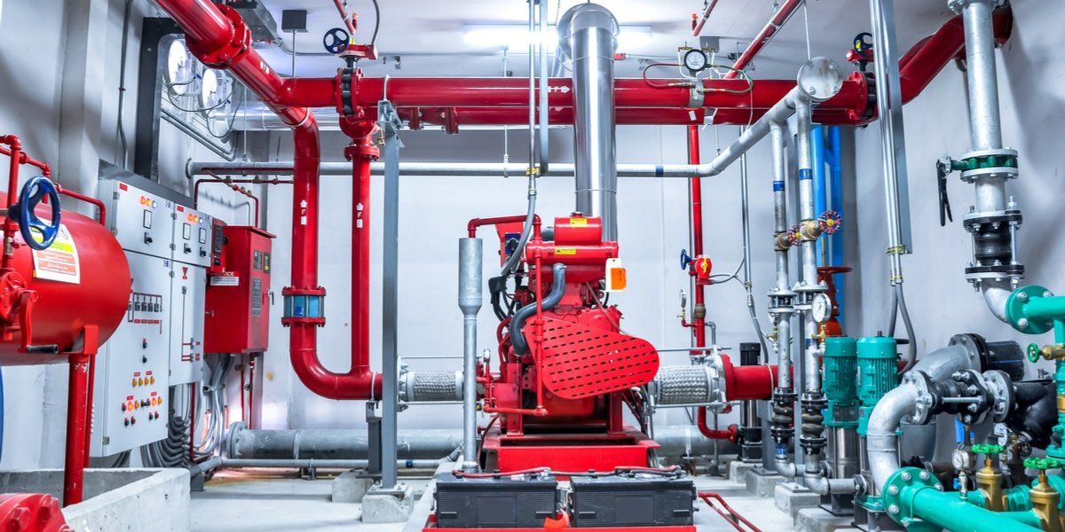Red fire suppression system in an industrial setting, with pipes, pumps, and control panels.