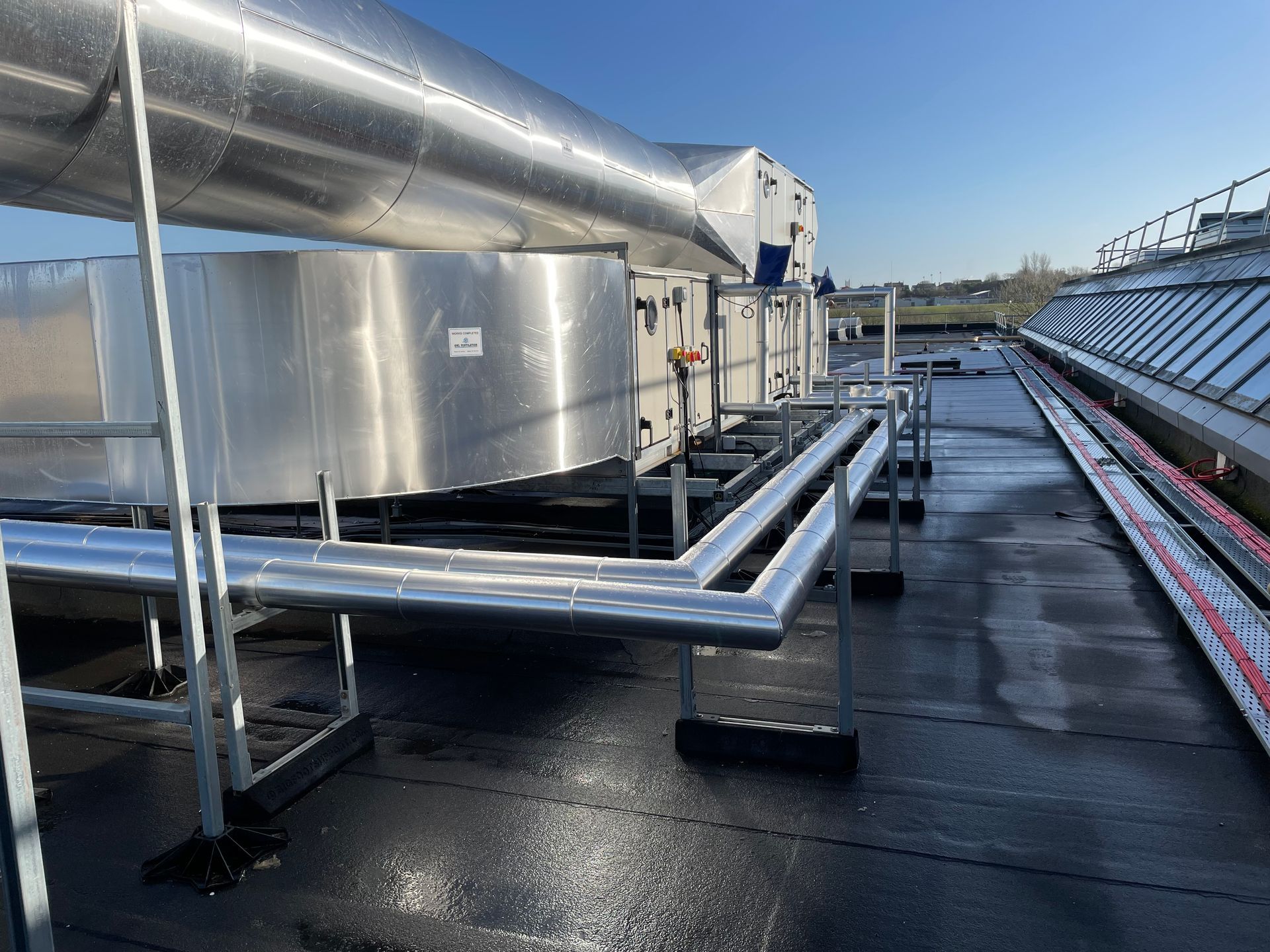 Rooftop HVAC system with insulated pipes and ductwork, sunny day.