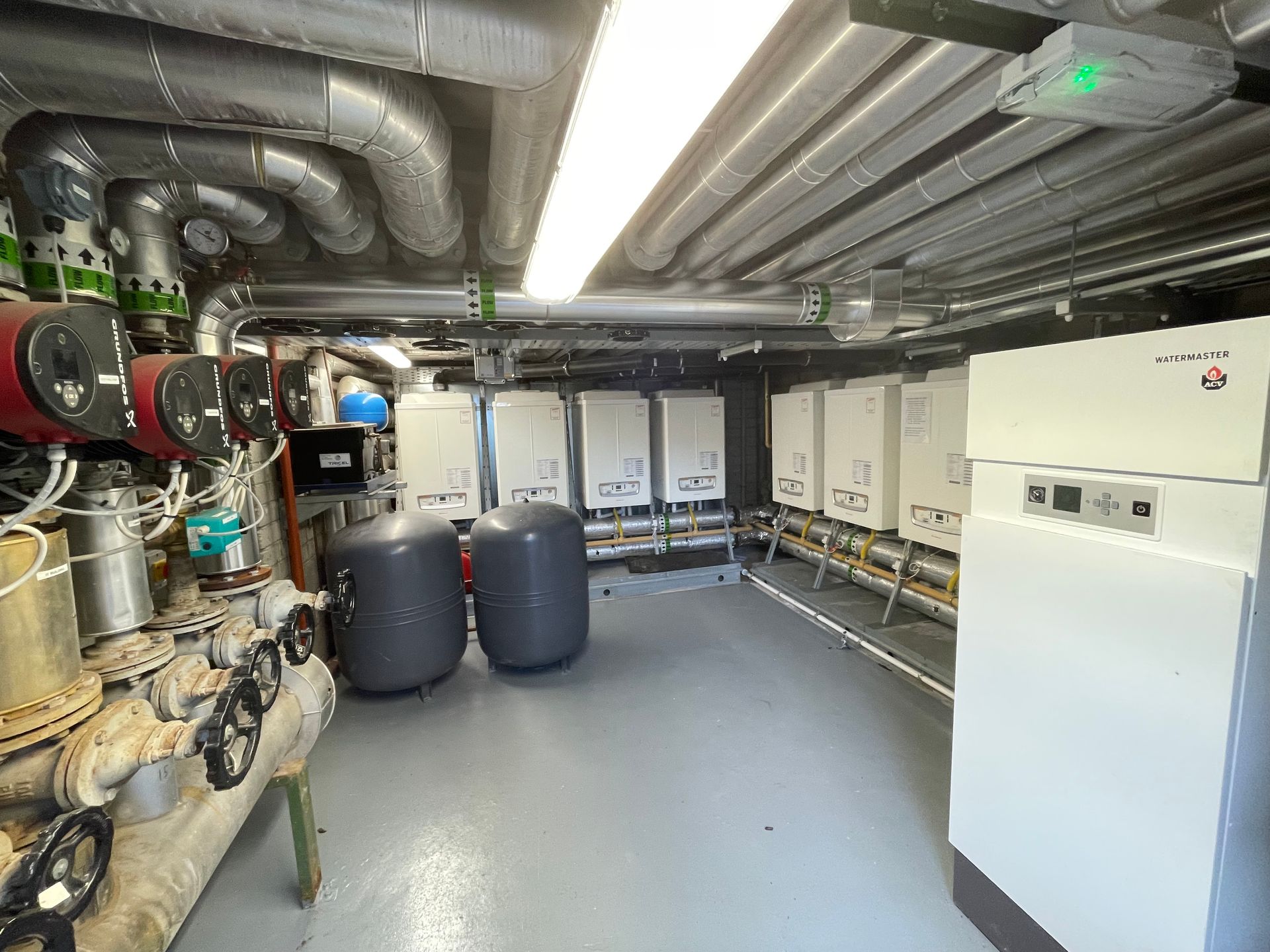 Industrial room with heating and cooling equipment; tanks, pipes, and control panels.