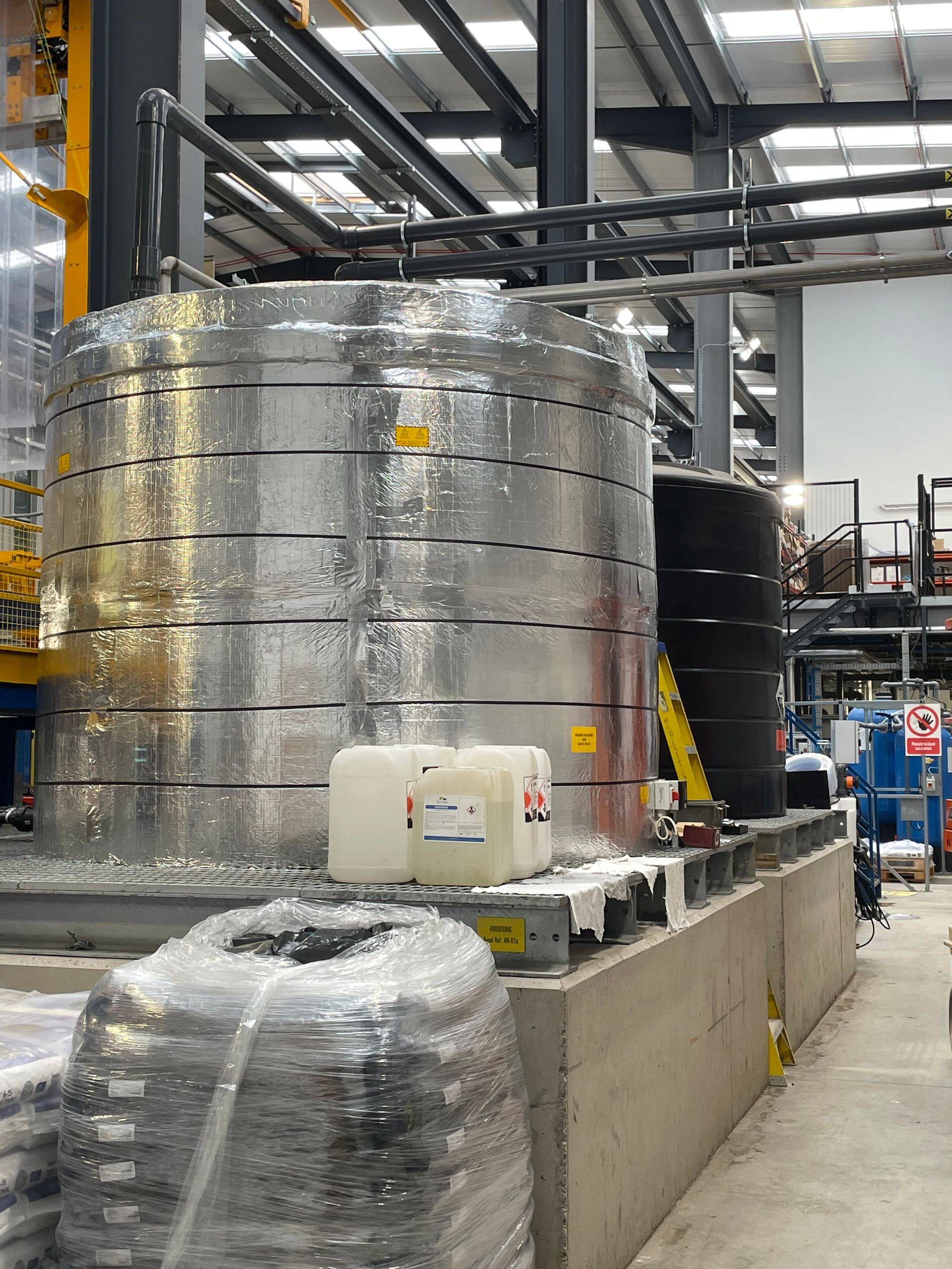 Large, silver industrial tank wrapped with reflective material in a factory setting.