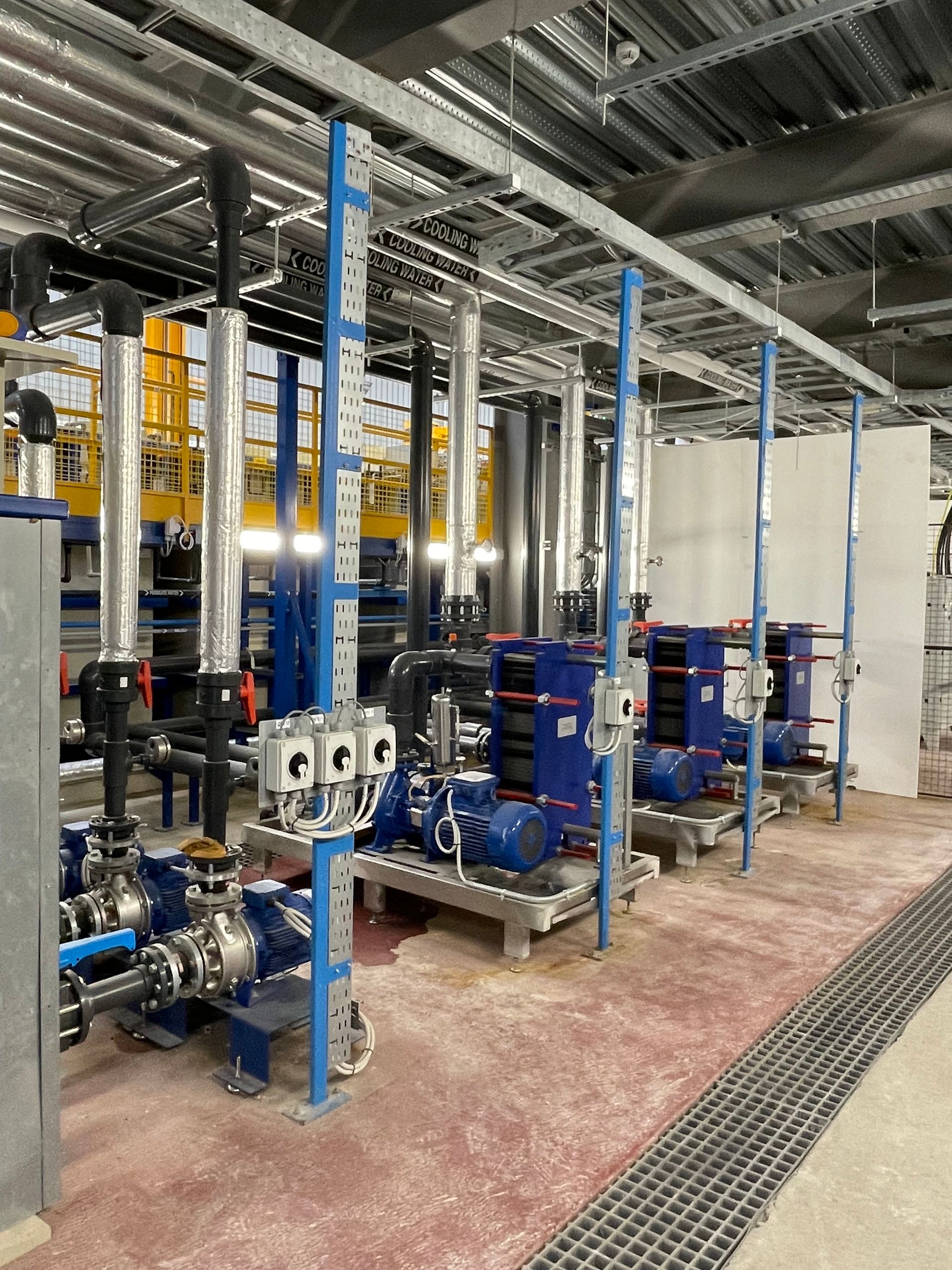 Industrial machinery with blue and silver pipes and equipment in a building.