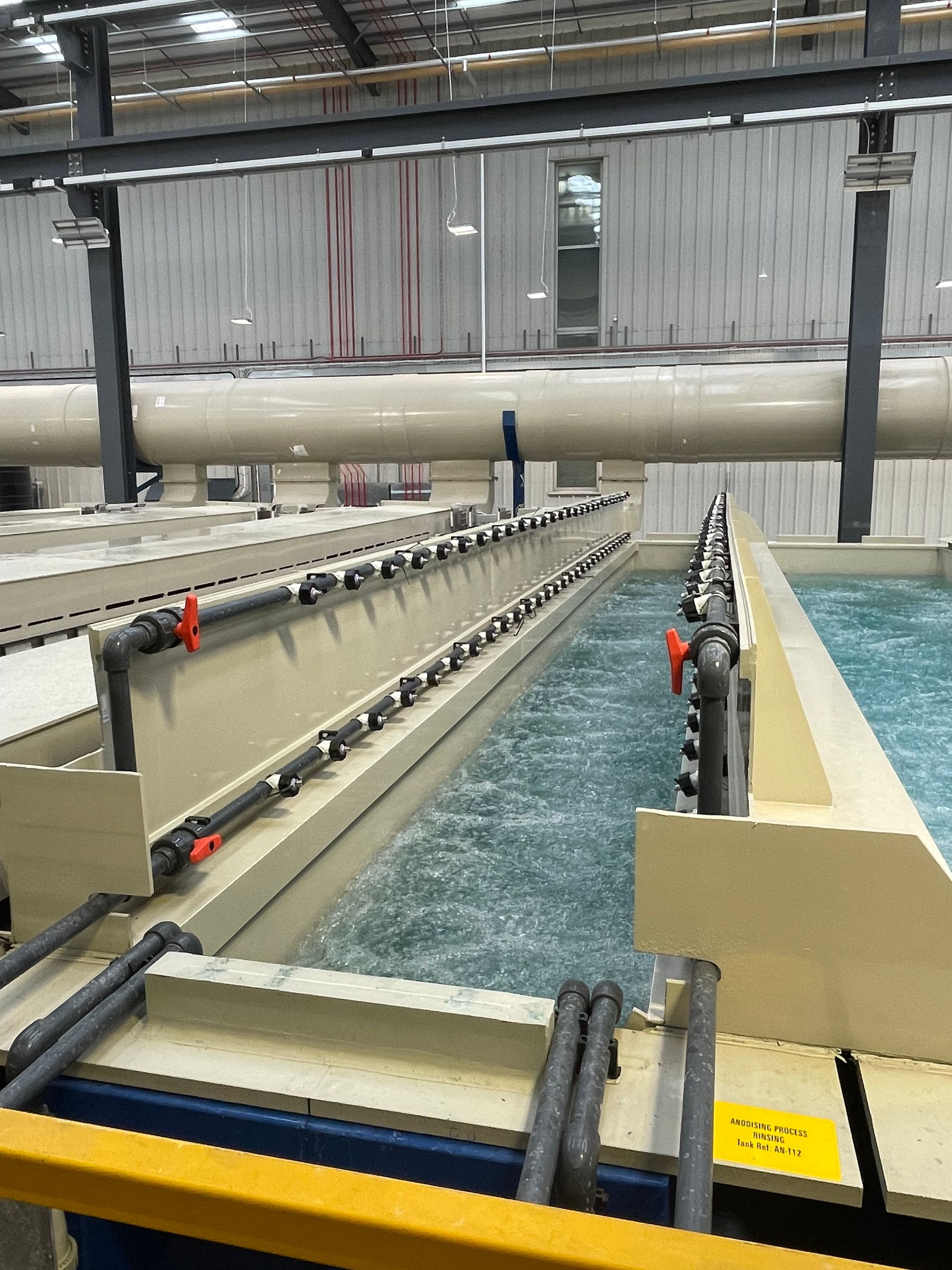 Large industrial tanks with bubbling turquoise liquid, likely for chemical processing.