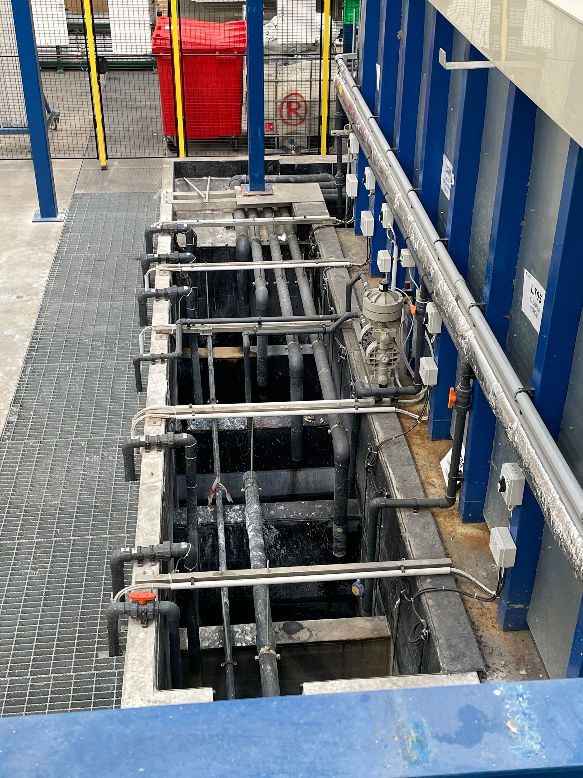 Industrial tanks and pipes in a factory setting, with walkways. Blue and white colors.
