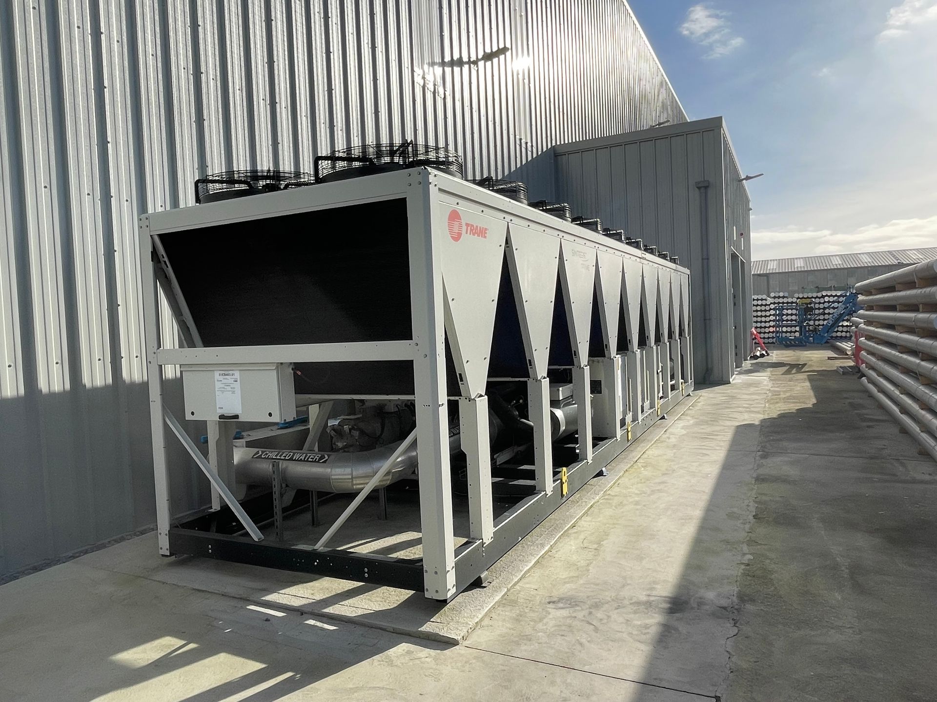 Gray industrial chiller unit outside a metal-clad building.